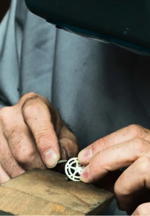 Person working on a small mechanical component with a magnifying glass.
